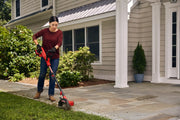 Photo of a person using a Craftsman CMCED400B lawn edger on a grass edge near a house walkway.
