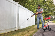 Photo of a person cleaning a white fence with a Craftsman CMEPW1900 pressure washer outdoors; product in foreground.